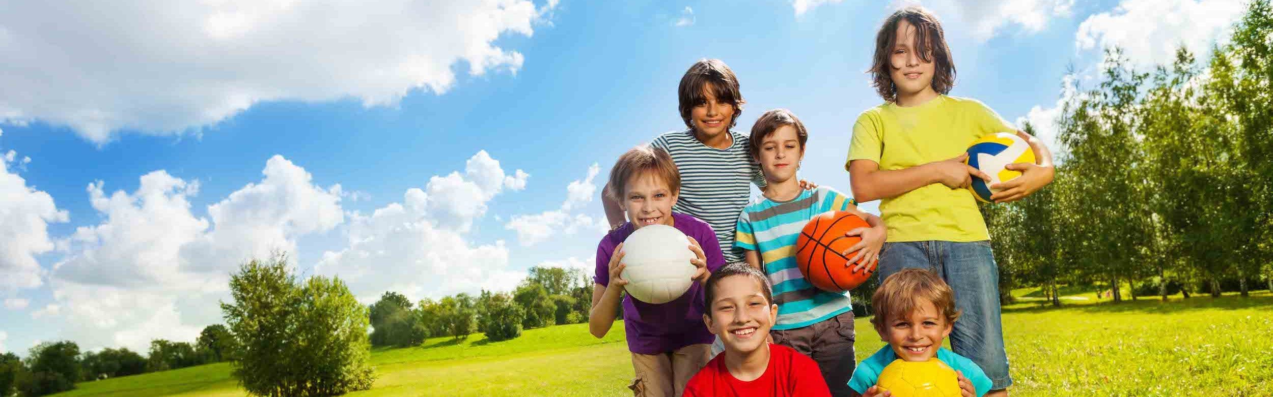 kids-with-ball six kids in a field holding balls