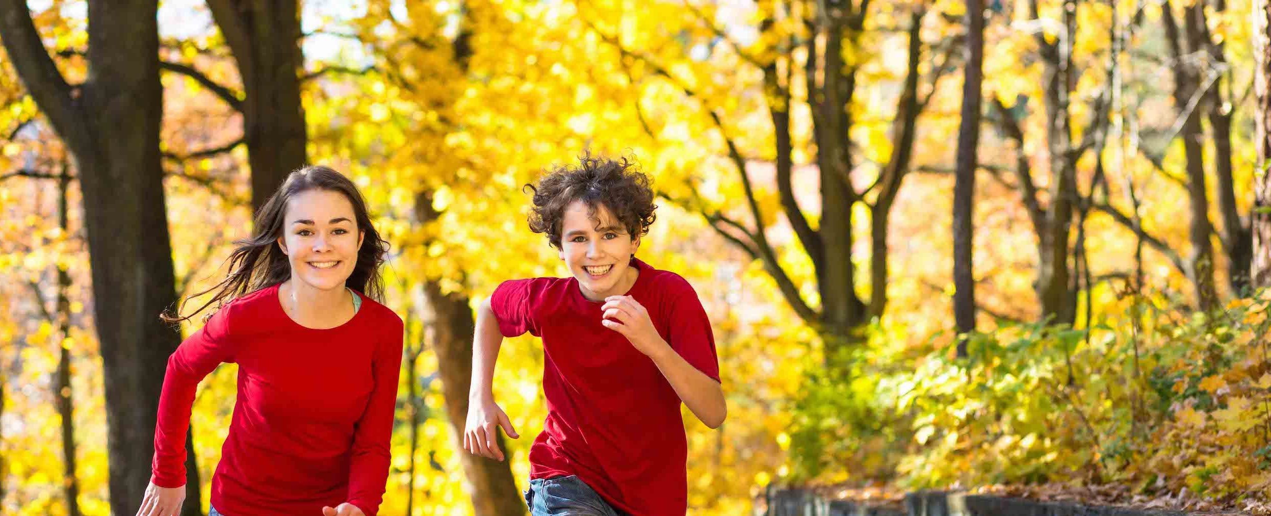 kids-running kids running down a path with fall leaves