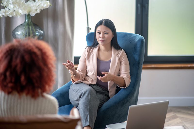 Asian professional female psychologist speaking with client Asian psychologist. Asian professional psychologist speaking with client while analyzing situation