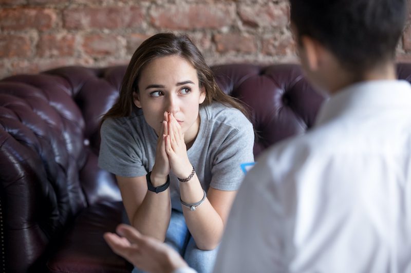Unhappy young girl at the psychologist Young woman visiting therapist counselor. Girl feeling depressed, unhappy and hopeless, needs assistance. Serious disease, unwilling pregnancy, abort or death of loved one, addiction to drugs concept
